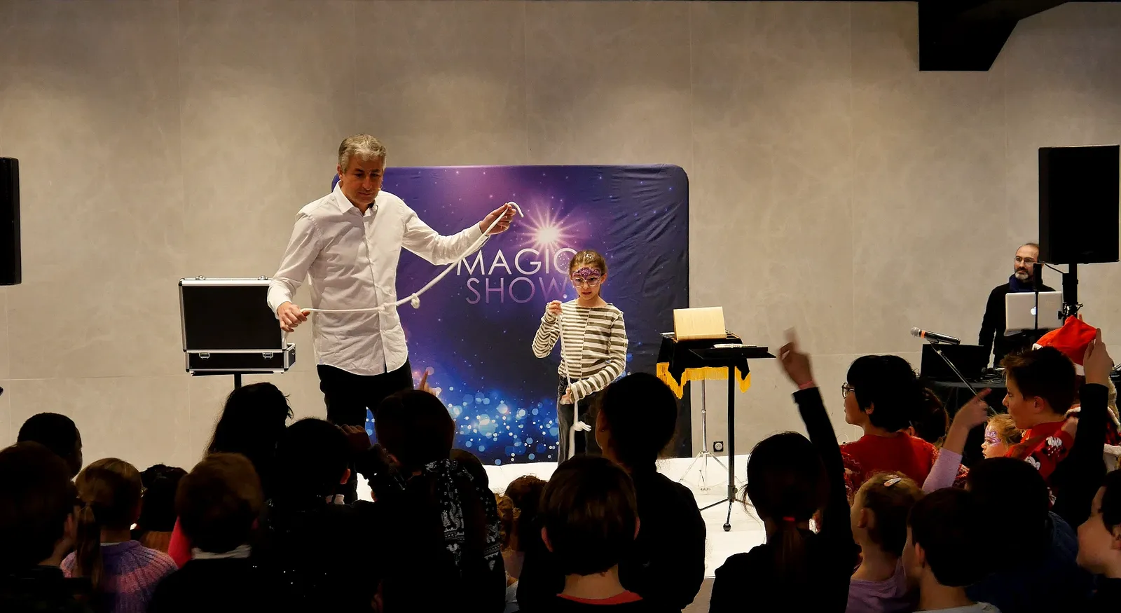 Ari fait participer une enfant sur scène pendant un spectacle de magie avec une corde